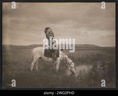 Eine Oase in den Badlands, 1905. Das Foto zeigt Red Hawk, einen Oglala-Krieger, der auf einem Pferd sitzt, das aus einem kleinen Teich in den Badlands von North Dakota trinkt. Stockfoto