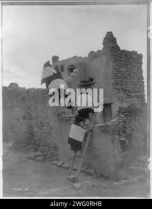 Walpi Homes-Hopi, 1907. Frauen klettern auf Leiter und Stufen des Pueblo-Bauens. Stockfoto