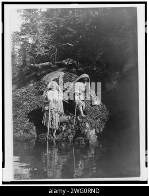 Sammeln von Algen-Clayoquot, 1910. Zwei Clayoquot-Indianer mit Körben am Wasser. Stockfoto