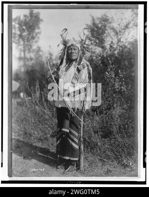 Long Time Dog-Hidatsa, 1908. Langhund, Porträt in voller Länge, stehend, nach vorne gerichtet, Kopfkragen getragen, Hemd aus Buckskin und Leggings mit Messingglocken. Stockfoto