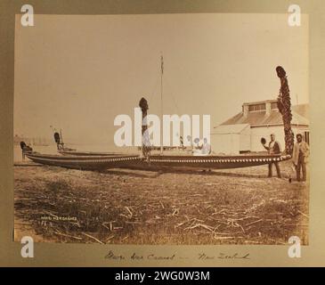 Maori-Kanus. Neuseeland. Vier Maori-Männer in europäischer Kolonialkleidung posieren neben zwei langen Kanus. Fahnenmast und Hafen dahinter. Von Charles Appleton Longfellow's Reise nach Neuseeland im Jahr 1891. Stockfoto