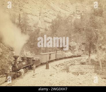 Riesen Bluff Elk Canyon auf Black Hills und ft P RR, 1890. Eine holzbrennende Lokomotive mit vier Wagen auf einer Schiene unter einer Klippe; mehrere Personen posieren vor dem Zug. Stockfoto