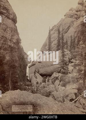 Unsere Picknickparty im Sunday Gulch fotografierte zwischen den Mauern der schönsten Berge der Dakotas, in der Nähe von Custer City auf dem B&amp; M Ry, 1891. Eine Gruppe von Männern und Frauen posierte auf Felsbrocken zwischen zwei riesigen Felsformationen. Stockfoto