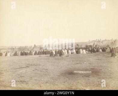 Indianerrat im feindlichen Lager, 1891. Rückansicht eines großen Halbkreises von Lakota-Männern, die auf dem Boden sitzen, mit Tipis im Hintergrund, wahrscheinlich auf oder in der Nähe des Pine Ridge Reservation. Stockfoto