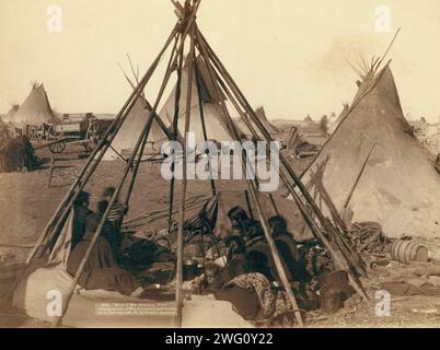 Das Haus von Mrs. American Horse, das Squaws in Mrs. A. Haus im feindlichen Lager besucht, 1891. Frauen und Kinder aus Oglala sitzen in einem offenen Tipi-Rahmen in einem Lager, die meisten schauen von der Kamera weg, wahrscheinlich auf oder in der Nähe des Pine Ridge Reservation. Stockfoto