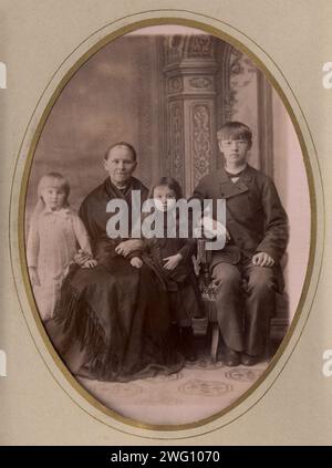 Ein Foto einer älteren Frau, eines jungen Mannes in einem Zivilanzug und zwei stehende Mädchen, Ende 19. Jh. - Anfang 20. Jh. Diese Sammlung von Fotografien und Dokumenten aus dem Privatarchiv von Sergej Michailowitsch Tschashchin bezieht sich auf die Einrichtung einer Feuerwehrstation in Ostsibirien im 19. Und frühen 20. Jahrhundert. Es umfasst Materialien über die Ausrüstung zur frühzeitigen Brandbekämpfung, die Organisation eines sibirischen Löschteams und die Leiter der ersten sibirischen Feuerwehr. Stockfoto