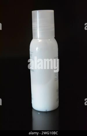 Damenkosmetik, kleine weiße Flasche Hautpflegecreme auf schwarzem Hochglanzhintergrund. Stockfoto