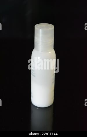 Damenkosmetik, kleine weiße Flasche Hautpflegecreme auf schwarzem Hochglanzhintergrund. Stockfoto