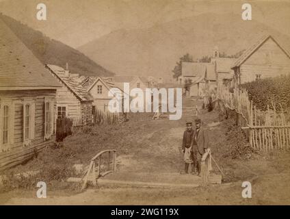 Hauptstraße in Petropavlovsk in Kamtschatka. Blick auf Mishennaya Sopka, 1890. Diese Sammlung besteht aus vierundvierzig Fotografien der Sachalin-Insel und der Stadt Petropavlovsk-Kamchatskii im späten 19. Und frühen 20. Jahrhundert. Die Fotografien zeigen Straßen, einzelne Gebäude, Panoramen der bewohnten Gebiete und lokale Menschen, darunter Sträflinge und Gefangene. Die Sammlung bietet Einblicke in die Wirtschaft, Gesellschaft und Lebensweise in dieser abgelegenen Ecke des Russischen Reiches um die Wende zum 20. Jahrhundert. Die Identität des Fotografen ist unbekannt. Kamtschatka Regional Stockfoto