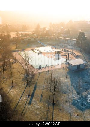 Die Morgensonne wirft lange Schatten über ein Schwimmbad mit frostbewachsenem Gras und Bäumen, ENCW Freibad Calw, Stammheim, Schwarzwald, Deutschland Stockfoto