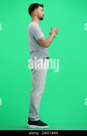 Ein Mann, voller Länge, auf grünem Hintergrund, fleht Stockfoto