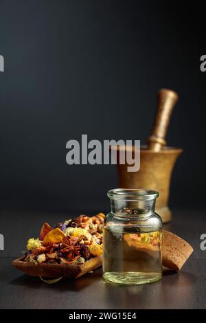 Ätherisches Öl oder Kräutertinktur in einer Glasflasche. Mischung aus getrockneten gesunden Heilkräutern und Heilpflanzen auf schwarzem Hintergrund. Leerzeichen kopieren. Stockfoto