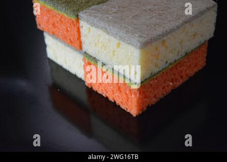 Dinge, die häufig im Haushalt verwendet werden. Farbige Waschlappen zum Waschen von Geschirr sind auf einem glänzend schwarzen Hintergrund angeordnet. Stockfoto