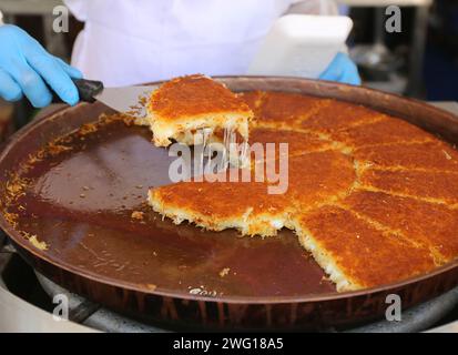 Knafeh (Kunefe) ist ein traditionelles Dessert aus dem Nahen Osten, das aus gesponnenem Gebäck namens Kataifi hergestellt wird, das in einem süßen Sirup auf Zuckerbasis namens Attar eingeweicht wird Stockfoto