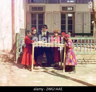 Gruppe jüdischer Kinder mit einem Lehrer Samarkand zwischen 1905 und 1915. Ethnische Vielfalt: Jüdische Kinder mit ihrem Lehrer. Samarkand, ein altes kommerzielles, intellektuelles und spirituelles Zentrum an der Seidenstraße von Europa nach China, entwickelte eine bemerkenswert vielfältige Bevölkerung, darunter Tadschiken, Perser, Usbeken, Araber, Juden und Russen. Samarkand und ganz Westturkestan wurden Mitte des 19. Jahrhunderts in das Russische Reich eingegliedert und haben seine ethnische Vielfalt bis heute bewahrt. Prokudin-Gorskii fängt hier eine Gruppe jüdischer Jungen in traditioneller Kleidung ein Stockfoto