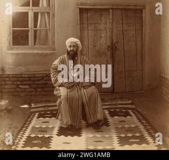 Elder, Samarkand, zwischen 1905 und 1915. Mann saß auf einem Stuhl, auf einem Teppich, vor einem Haus (?). Im Album: Views in Central Asia, Russian Empire, LOT 10338, No 132. Stockfoto