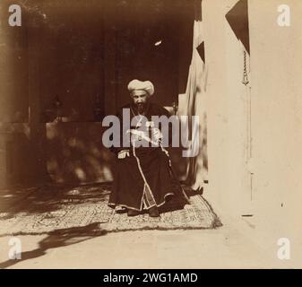 Elder, Samarkand, zwischen 1905 und 1915. Mann sitzt auf Stuhl, auf Teppich, draußen. Im Album: Views in Central Asia, Russian Empire, LOT 10338, No 133. Stockfoto