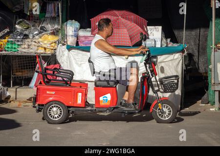 SAMUT PRAKAN, THAILAND, 07. Dezember 2023, Ein Mann fährt ein Elektrodreirad auf dem Markt Stockfoto