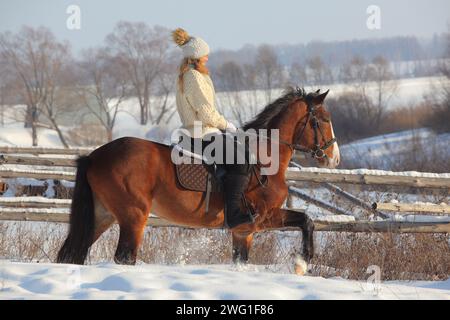 Mädchen galoppiert auf einem Pferd auf der schneebedeckten Winterranch Stockfoto