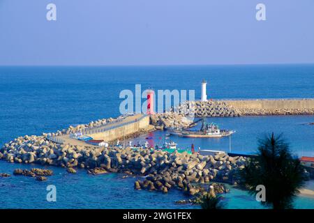 Samcheok City, Südkorea - 28. Dezember 2023: Mit Blick auf den Hafen von Galnam, die zwei Wellenbrecher, gekrönt von roten und weißen Leuchttürmen, führen Sie die Boote zu Stockfoto