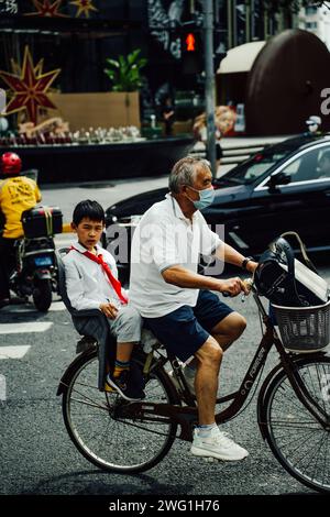 Kleiner Junge auf einem Fahrrad hinter seinem Großvater in Shanghai, China Stockfoto