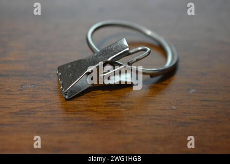 Eine kleine Metallkrabbe mit einem großen Ring wird zum Befestigen von Vorhängen verwendet und befindet sich auf einem Holztisch. Stockfoto