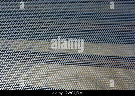 Metallgitter, Hintergrund, mit runden identischen Löchern, Metallstruktur mit Schatten und Licht. Stockfoto