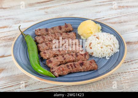 Türkische Küche inegol Fleischbällchen. Gegrillte Fleischbällchen auf einem Teller. Türkischer Tekirdag oder Inegol Kofte mit Pfeffer, Reis und Kartoffelpüree, Kofta. Stockfoto