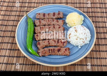 Türkische Küche inegol Fleischbällchen. Gegrillte Fleischbällchen auf einem Teller. Türkischer Tekirdag oder Inegol Kofte mit Pfeffer, Reis und Kartoffelpüree, Kofta. Stockfoto