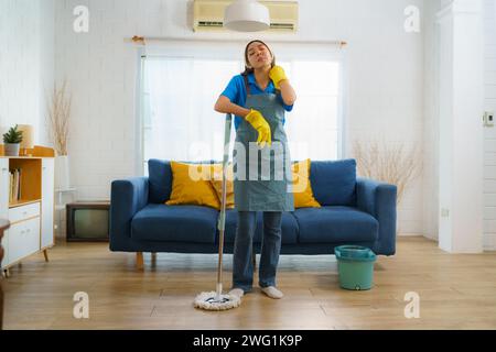 Die Haushälterin, die den Boden im Wohnzimmer müde reinigt, spiegelt die harte Arbeit und den Einsatz des Reinigungsteams wider und zeigt das Engagement für Stockfoto