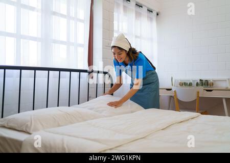 Die Haushälterin arrangiert und glättet die Bettwäsche in einem Schlafzimmer professionell und engagiert das Housekeeping-Team Stockfoto