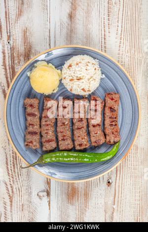 Türkische Küche inegol Fleischbällchen. Gegrillte Fleischbällchen auf einem Teller. Türkischer Tekirdag oder Inegol Kofte mit Pfeffer, Reis und Kartoffelpüree, Kofta. Stockfoto