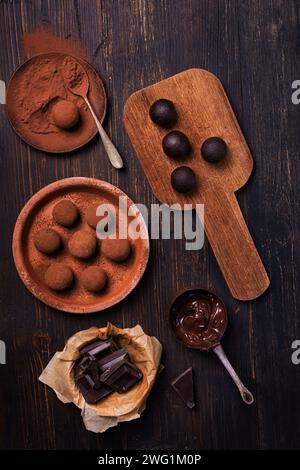 Leckere dunkle Schokoladentrüffel mit Kakaostaub auf braunem Hintergrund Stockfoto