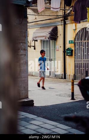 Ein kleiner Junge, der auf der Straße ins Seil springt, Shangai, China Stockfoto