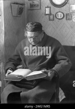 Ein älterer Mann sitzt und liest ein Buch, 1880-1910. Stockfoto