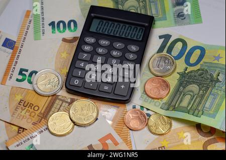 Euro-Banknoten und -Münzen mit vollständig sichtbarem Rechner eingeschaltet Stockfoto