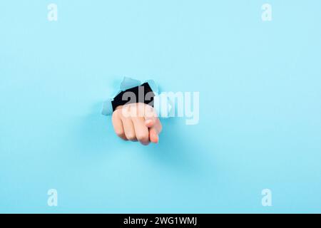 Finger zeigt nach vorne, Kopierraum für Werbung und Marketing, Aufmerksamkeitsgeste, blaues Papierloch Stockfoto