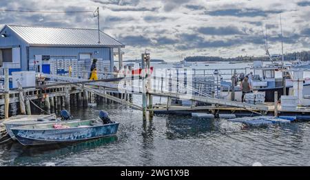 Lobster Dock: Ein Fischerboot an einem funktionierenden New England Dock lädt Hummer in Lagerkästen ab, die später in der Nähe des Piers unter Wasser liegen. Stockfoto