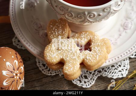 Hausgemachter Linzer-Keks in Form eines Hasen in der Nähe einer Tasse Tee, mit Osterei im Vordergrund Stockfoto