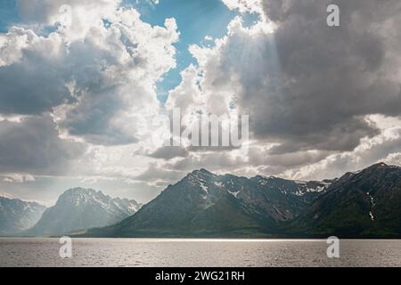 Dramatische Sonnenstrahlen, Wolken und schneebedeckte Berge über dem Jackson Lake im Grand Teton National Park Stockfoto