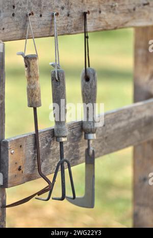 Rostige Gartengeräte hängen auf dem Holzgestell Stockfoto