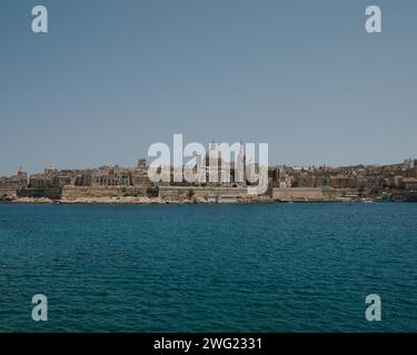 Valletta, die Hauptstadt von Malta im Sommer, ab Tigne Point, zeigt die Basilika unserer Lieben Frau vom Karmel und das türkisfarbene Mittelmeer. Stockfoto