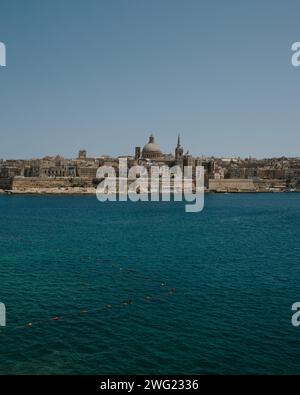 Valletta, die Hauptstadt von Malta im Sommer, ab Tigne Point, zeigt die Basilika unserer Lieben Frau vom Karmel und das türkisfarbene Mittelmeer. Stockfoto