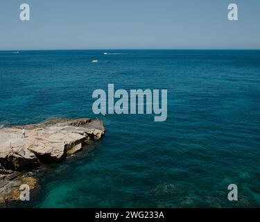 Ein Mann läuft an einem Felsvorsprung entlang und blickt auf das Mittelmeer in Malta. Stockfoto