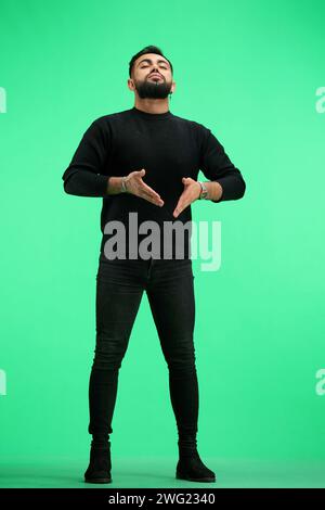 Ein Mann in voller Höhe, auf grünem Hintergrund, meditiert Stockfoto
