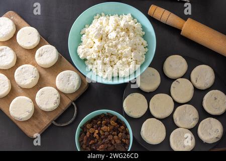 Käsekuchen aus Hüttenkäse und Rosinen. Bereiten Sie Speisen für das Frühstück zu. Syrnik-Pfannkuchen. Runder Käsekuchen auf schwarzem Hintergrund Stockfoto
