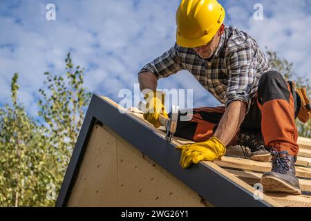 Kaukasischer professioneller Dachdecker und sein Job. Dachdesign. Stockfoto