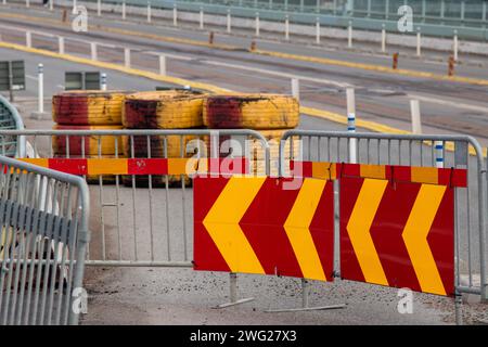 Schild für Umlenkung von Verkehr und Reifen als Hindernisse auf einer Straßenbaustelle. Gelbes und rotes Warnschild in der Nähe einer Brücke. Stockfoto