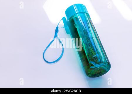 Kaltgebrühter grüner Tee in türkisfarbener wiederverwendbarer Flasche auf pastellweißem Hintergrund selektiver Fokus. Erfrischendes, nicht-alkoholisches Eisgetränk-Branding-Mockup. Reparieren Stockfoto