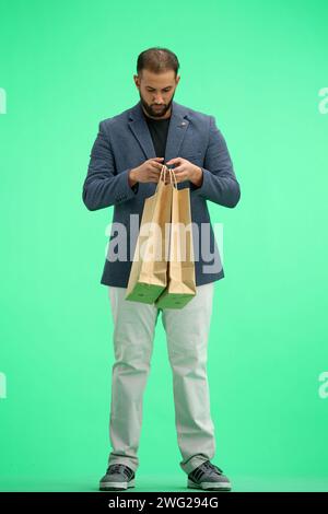 Ein Mann in voller Länge, auf grünem Hintergrund, mit Taschen Stockfoto